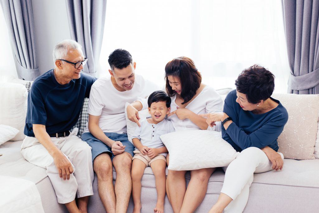 Happy Asian extended family sitting on sofa together, posing for group photos