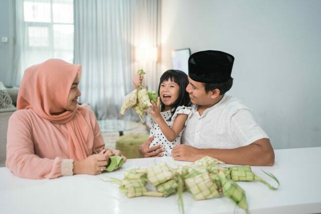 happy asian muslim family making ketupat together at home