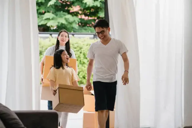 Asian family moving into their new home while organizing belongings after finding cheap storage space for rent in Singapore.